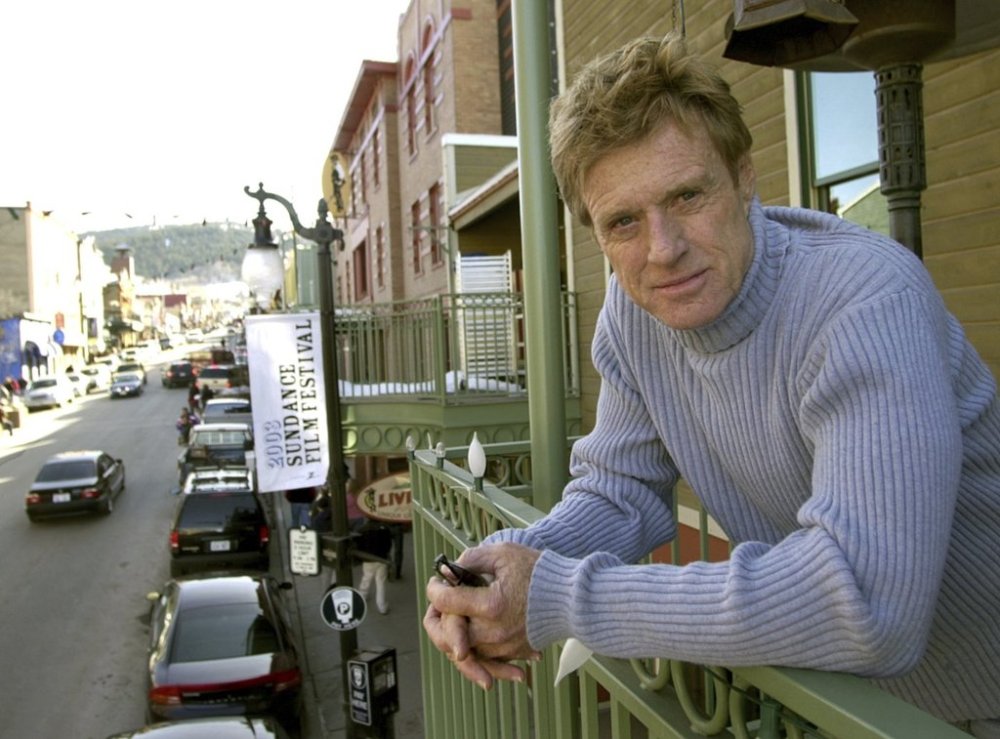 FILE - Robert Redford poses on a balcony along Main Street decorated with his Sundance Film Festival banners on Jan. 17, 2003, in Park City, Utah. (AP Photo/Douglas C. Pizac, File)