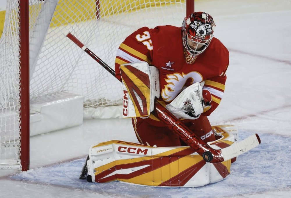 Calgary Flames goalie Dustin Wolf (32) gets his stick on a shot from the Vegas Golden Knights during second-period NHL hockey action in Calgary on Tuesday, April 15, 2025. THE CANADIAN PRESS/Jeff McIntosh
