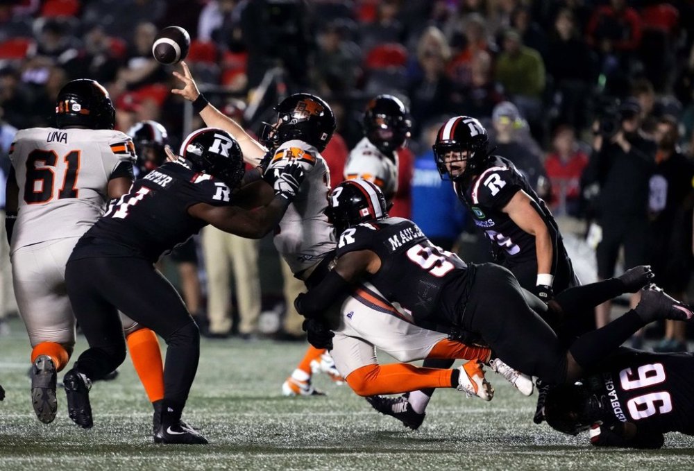 B.C. Lions quarterback Nathan Rourke (12) throws the ball as he is tackled by Ottawa Redblacks defensive lineman Lorenzo Mauldin IV (94) during second half CFL football action in Ottawa on Friday, Sept. 5, 2025. THE CANADIAN PRESS/Justin Tang