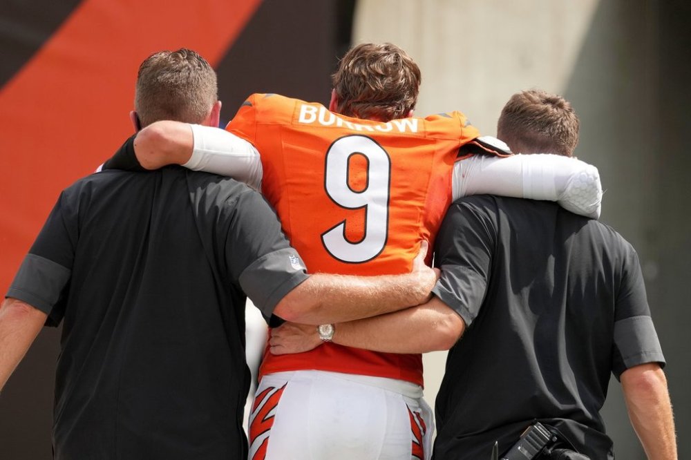 FILE - Cincinnati Bengals quarterback Joe Burrow, center, is helped off the field after suffering an injury during the second quarter of an NFL football game against the Jacksonville Jaguars, Sunday, Sept. 14, 2025, in Cincinnati. (AP Photo/Kareem Elgazzar, File)