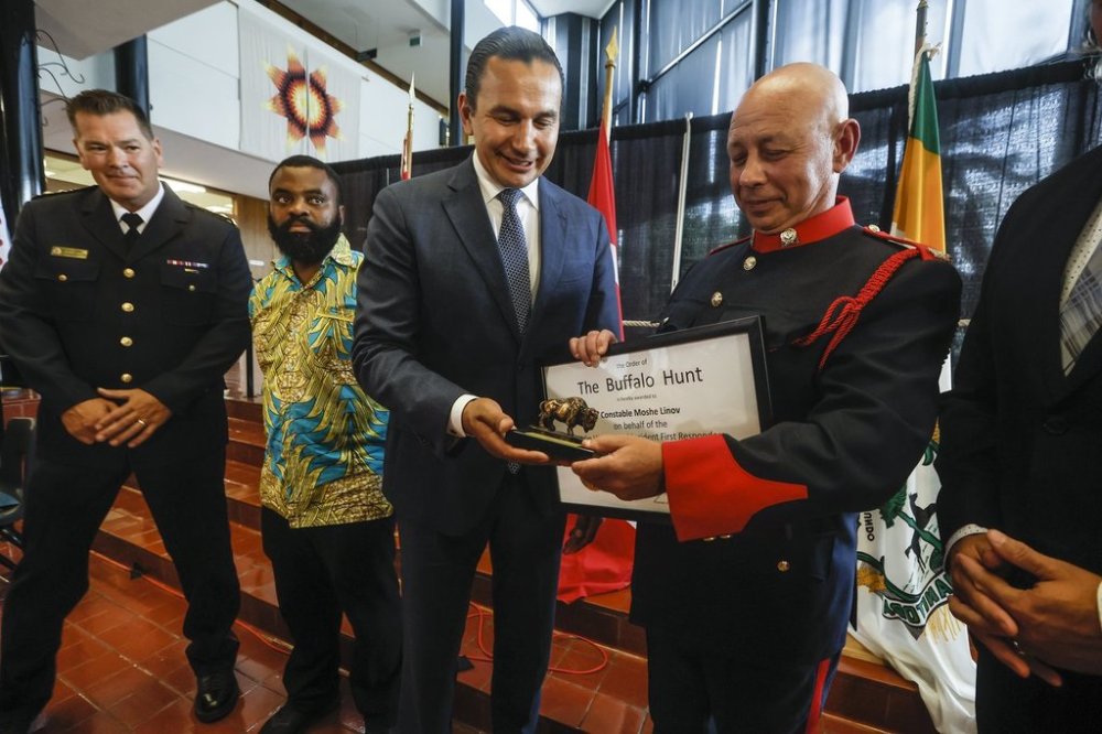 Manitoba Premier Wab Kinew awards the Order of the Buffalo Hunt to Const. Moshe Linov, Brandon Police Service, who represented the first responders involved in a sword attack inside a high school in June, at the Brandon City Hall in Brandon, Man. on Thursday, July 24, 2025. THE CANADIAN PRESS/John Woods