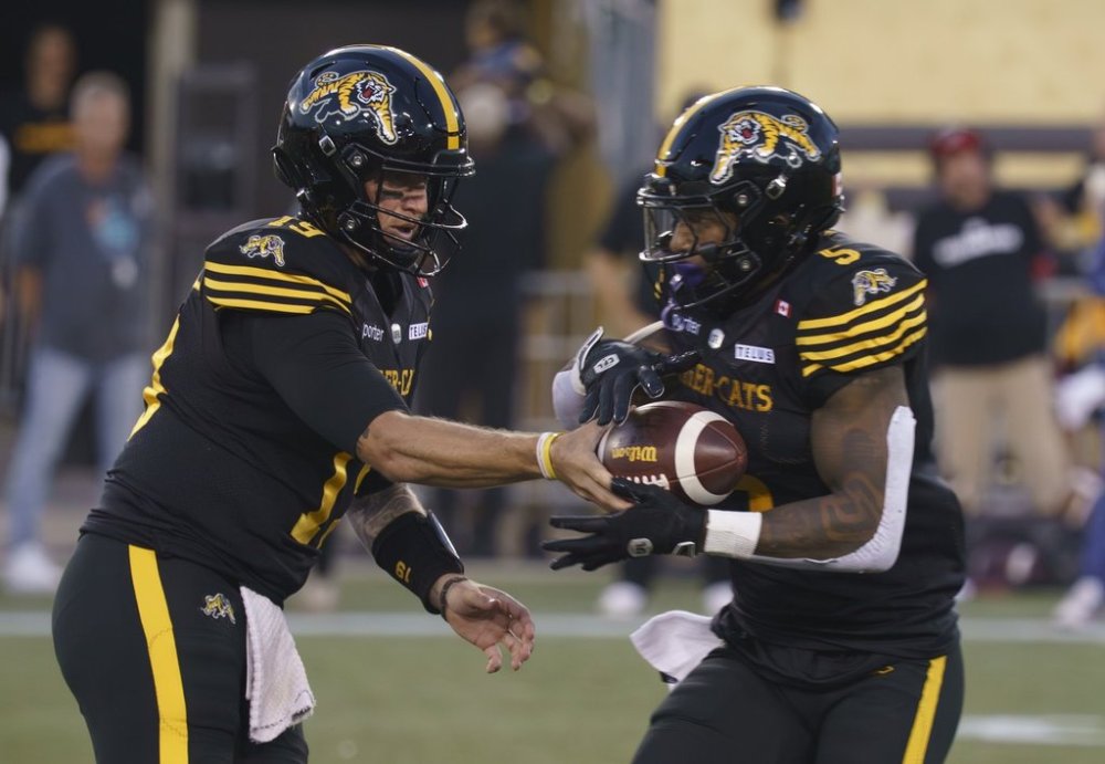 Hamilton Tiger-Cats quarterback Bo Levi Mitchell (19) hands off to running back Greg Bell (5) during first half CFL football game action against the Winnipeg Blue Bombers in Hamilton, Ont. on Friday, Sept. 12, 2025. THE CANADIAN PRESS/Peter Power