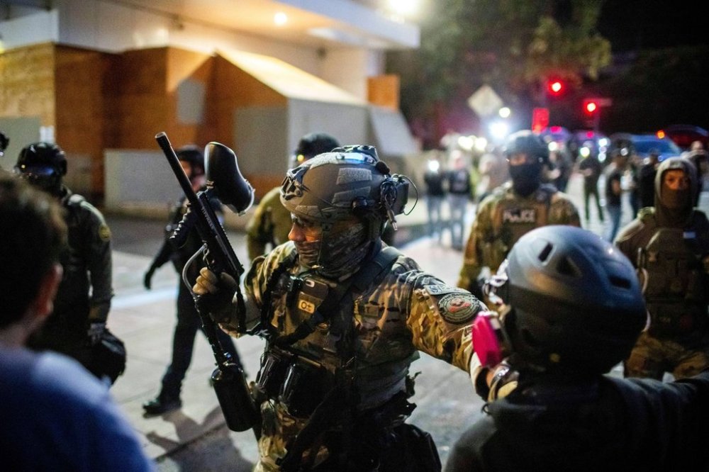 Police and Federal officers stand guard an area by the U.S. Immigration and Customs Enforcement facility in Portland, Ore. on Sunday, October. 5, 2025. (AP Photo/Ethan Swope)