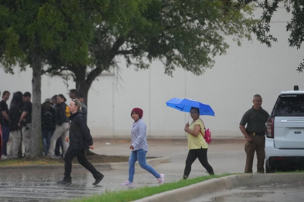 People gather with police at a staging area near a U.S. Immigration and Customs Enforcement office after a reported shooting, in Dallas on Wednesday, Sept. 24, 2025. (AP Photo/Julio Cortez)