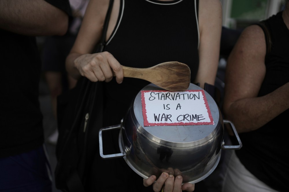 An Israeli activist bangs a pot with a wooden spoon to protest the starvation of Palestinian civilians in the Gaza Strip, outside the U.S. Embassy branch office in Tel Aviv, Israel, on July 24. (The Associated Press)
