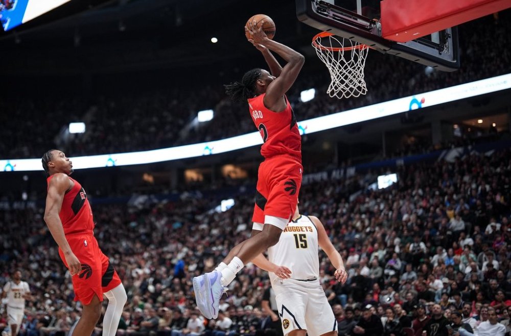 Toronto Raptors' Jonathan Mogbo, front right, dunks the ball as Scottie Barnes, left, and Denver Nuggets' Nikola Jokic, back right, watch during the first half of a preseason NBA basketball game, in Vancouver, B.C., Monday, Oct. 6, 2025. THE CANADIAN PRESS/Darryl Dyck