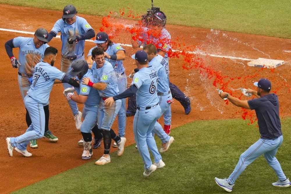 Toronto Blue Jays' Alejandro Kirk (fourth left) is congratulated by teammates after hitting an RBI sacrifice fly to defeat the Baltimore Orioles during ninth inning MLB baseball action, in Toronto on Saturday, September 13, 2025. THE CANADIAN PRESS/Chris Young