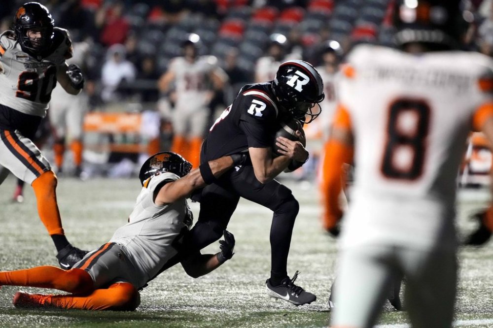 Ottawa Redblacks quarterback Dustin Crum (18) runs with the ball to score a touchdown as B.C. Lions linebacker Josh Woods (2) tries to tackle, during second half CFL football action in Ottawa on Friday, Sept. 5, 2025. THE CANADIAN PRESS/Justin Tang
