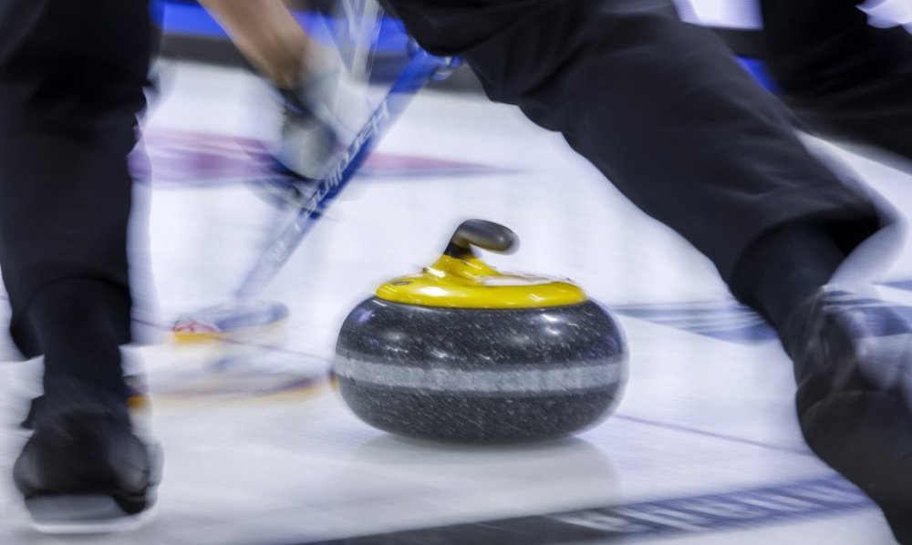 Players sweep a rock at the Tim Hortons Brier in Lethbridge, Alta., Sunday, March 6, 2022. A network of curling high-performance training centres in Canada has been created with expansion to Victoria, Okotoks, Alta., Moose Jaw, Sask., and Kitchener-Waterloo, Ont. THE CANADIAN PRESS/Jeff McIntosh