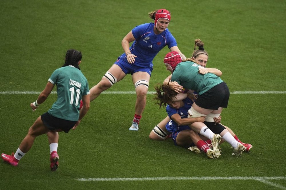 Ireland's Aoife Wafer, right, is tackled by France's Morgane Bourgeois, bottom, and her teammate Lea Champon during a Women's Rugby World Cup 2025 quarterfinal match between France and Ireland, in Exeter, England, Sunday, Sept. 14, 2025. (AP Photo/Alastair Grant)