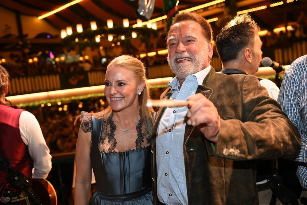 Arnold Schwarzenegger and his partner, Heather Milligan stand on stage during the 190th Oktoberfest on Friday, Sept. 26, 2025, in Munich, Germany. (Felix Hörhager/dpa via AP)
