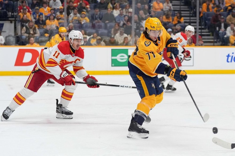 Nashville Predators right wing Luke Evangelista (77) passes the puck past Calgary Flames centre Mikael Backlund (11) during the third period of an NHL hockey game Saturday, Nov. 1, 2025, in Nashville, Tenn. (AP Photo/Camden Hall)
