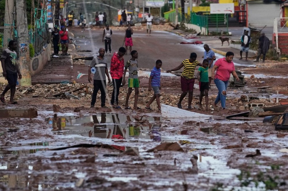 People walk through Santa Cruz, Jamaica, Wednesday, Oct. 29, 2025, after Hurricane Melissa passed. (AP Photo/Matias Delacroix),