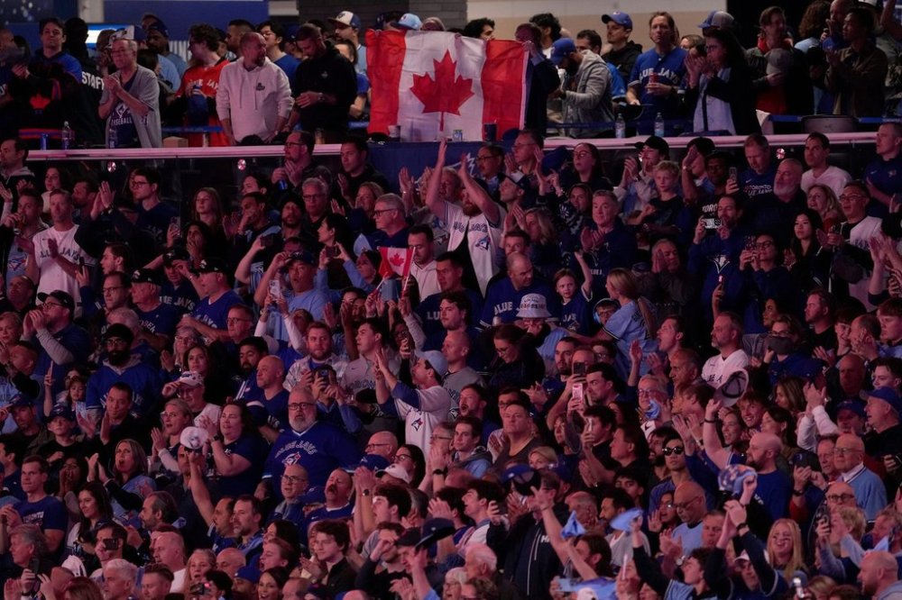 Fans wave the Canadian flag during the national anthem prior to Game 2 of baseball's World Series between the Los Angeles Dodgers and the Toronto Blue Jays, Saturday, Oct. 25, 2025, in Toronto. (AP Photo/David J. Phillip)