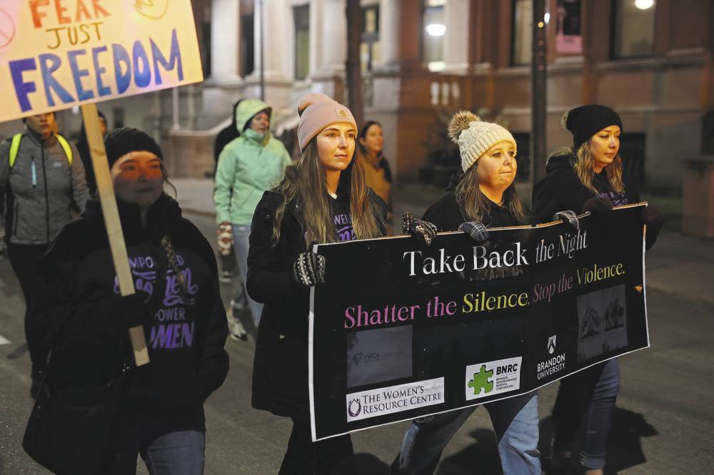 Jamie Brown (centre), co-ordinator of the women and gender equality program at the Western Manitoba Women’s Centre, carries a banner during the 2024 Take Back The Night March in Brandon. (Tim Smith/The Brandon Sun files)
