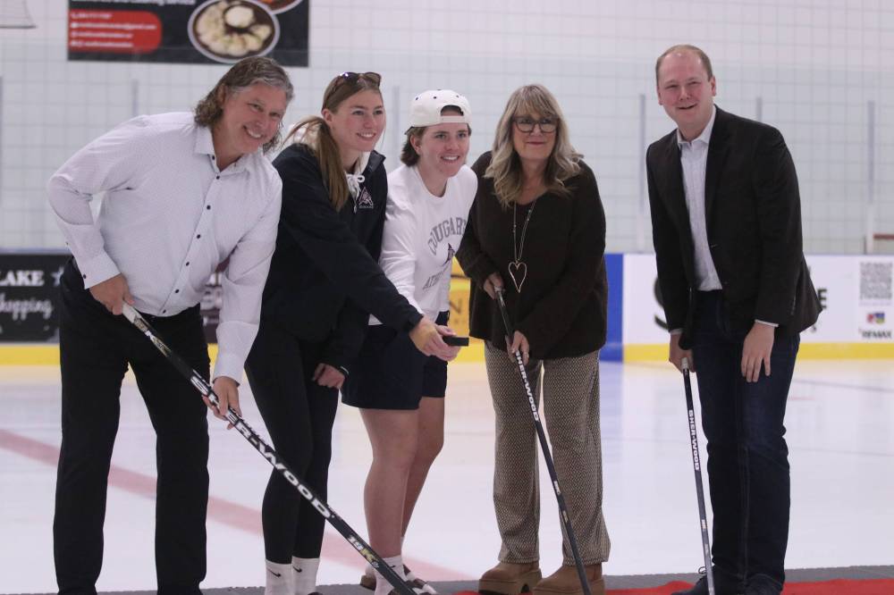 Brandon Mayor Jeff Fawcett (left), Spruce Woods MLA Colleen Robbins (second right) and Brandon-Souris MP Grant Jackson (right) hold hockey sticks while Assiniboine College hockey players Jenna Walker (middle) and Kylee Emms-Finnsson hold the puck during the reopening of the Sportsplex arena on Saturday afternoon. (Abiola Odutola/The Brandon Sun)