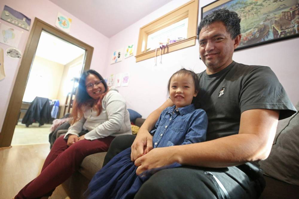 Ryan Choken holds his youngest child, four-year-old daughter Guenhwyvar, while sitting with his wife, Audrey Huang, and speaking to The Brandon Sun on Tuesday morning in their living room. (Matt Goerzen/The Brandon Sun)