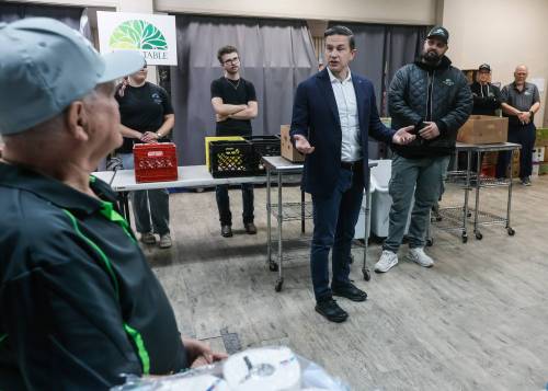 Conservative Leader Pierre Poilievre talks to volunteers as he fills food baskets at Agape Table, a local non-profit food bank in Winnipeg, on Monday. Poilievre toured the facility, filled weekly food baskets and met with staff and volunteers. (John Woods/Winnipeg Free Press)