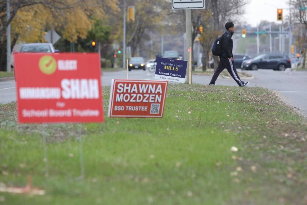 While crossing 18th Street in front of Brandon University on Tuesday afternoon, a pedestrian passes several election signs with names of individuals running in the Brandon School Division byelection, which will be held on Thursday. (Matt Goerzen/The Brandon Sun)