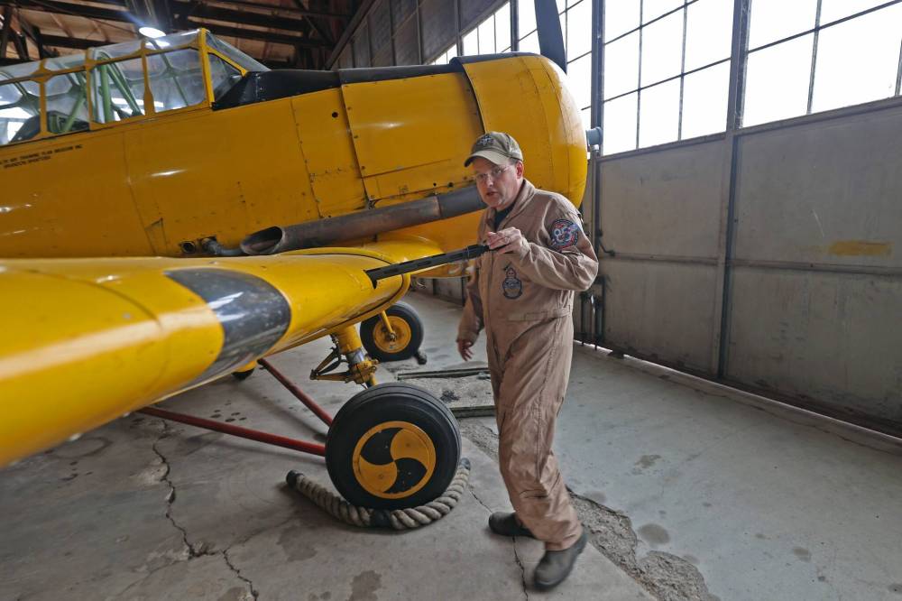 Chief pilot at the Commonwealth Air Training Plan Museum, Jeff Bell, holds a mounted machine gun on a Harvard MkII airplane from the Second World War era. (Connor McDowell/The Brandon Sun)