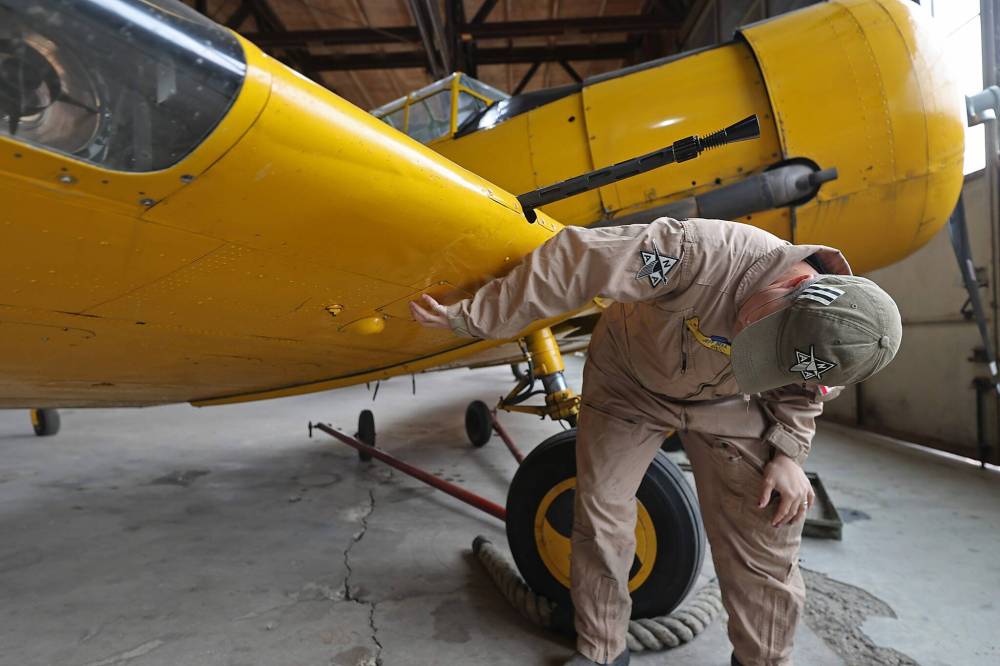 Jeff Bell gestures to where spent shell casings would be discarded from the mounted machine gun on the wing of a Harvard MkII aircraft. The plane was used by RCAF in the Second World War era. (Connor McDowell/The Brandon Sun)