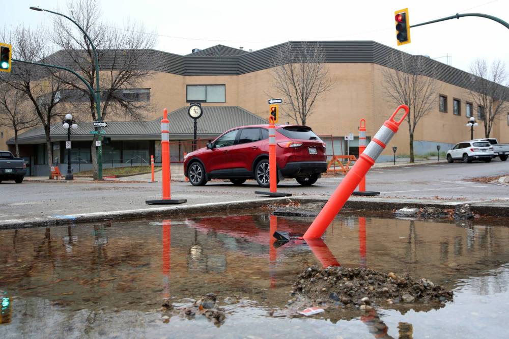 An SUV is driven past excess water from a water-valve discharge along Rosser Avenue. Crews will repair multiple water valves in the area of Ninth Street and Rosser Avenue next week. (Alex Lambert/The Brandon Sun)