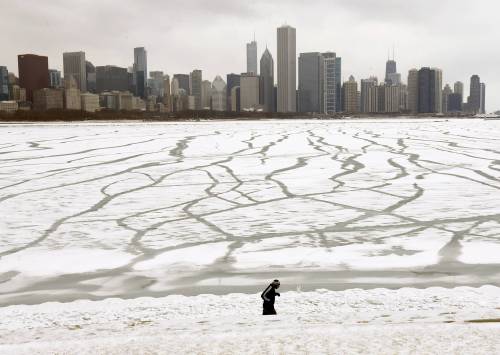 A lone jogger runs in the snow near the Adler Planetarium and Monroe Harbor along Lake Michigan in Chicago in January 2016. (The Associated Press files)