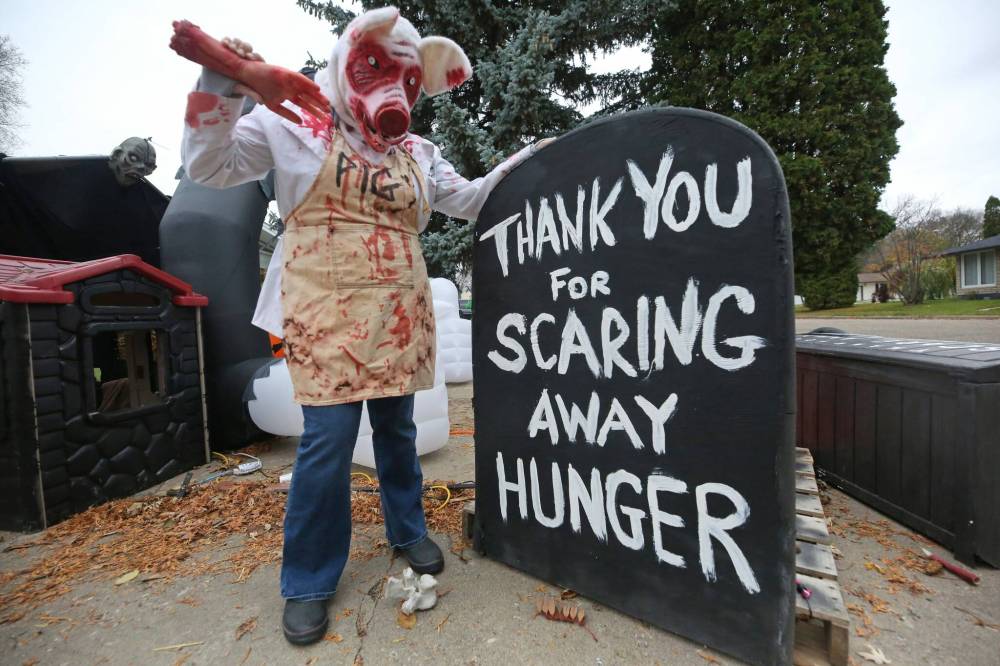 Dressed in her Scare Away Hunger event costume, Cedar Bay residence co-owner Carla Mitchell poses for a shot with one of the many signs that dot the Halloween-themed attraction. (Matt Goerzen/The Brandon Sun)