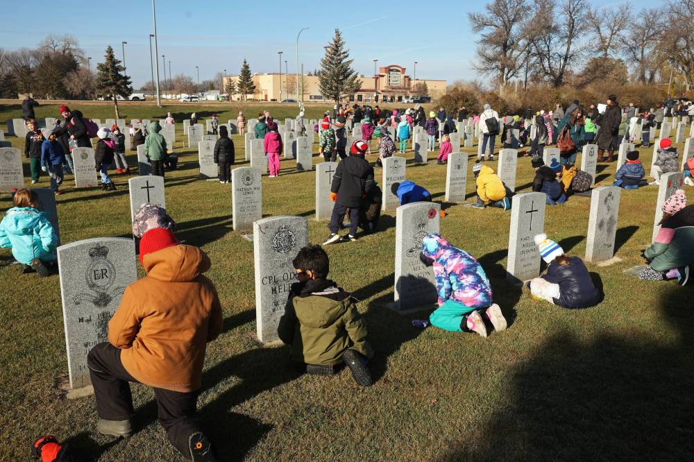 Students place poppies at the base of military gravestones during last year’s No Stone Left Alone event in Brandon. (Tim Smith/The Brandon Sun files)