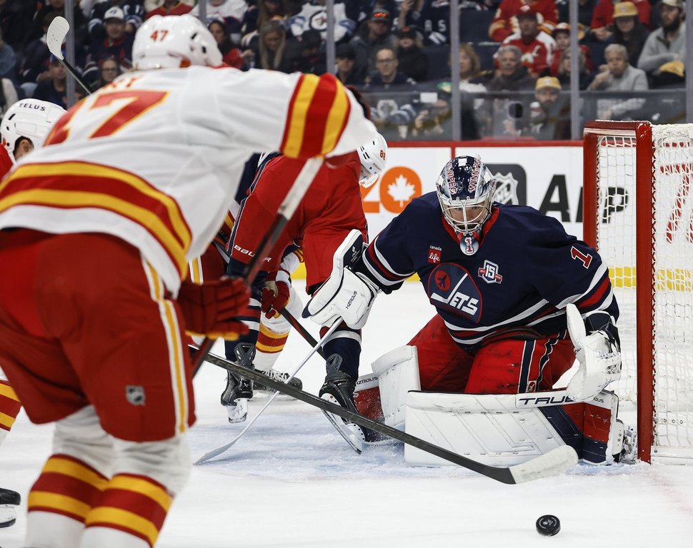 Winnipeg Jets goaltender Eric Comrie (1) keeps his eye on the puck during first period NHL action against the Calgary Flames in Winnipeg on Friday, Oct. 24, 2025. THE CANADIAN PRESS/John Woods