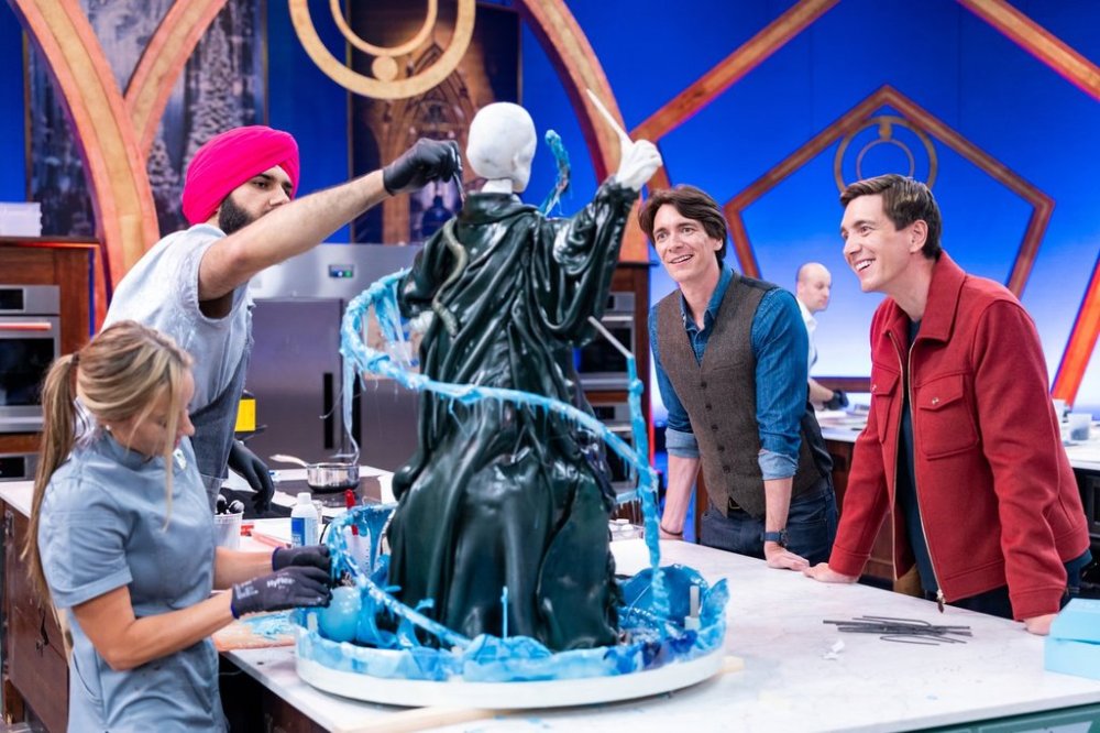 This image released by Food Network shows hosts Oliver Phelps, right, and James Phelps, watching contestants Katie Bonzer, left, and Jujhar Mann on the set of the competition series