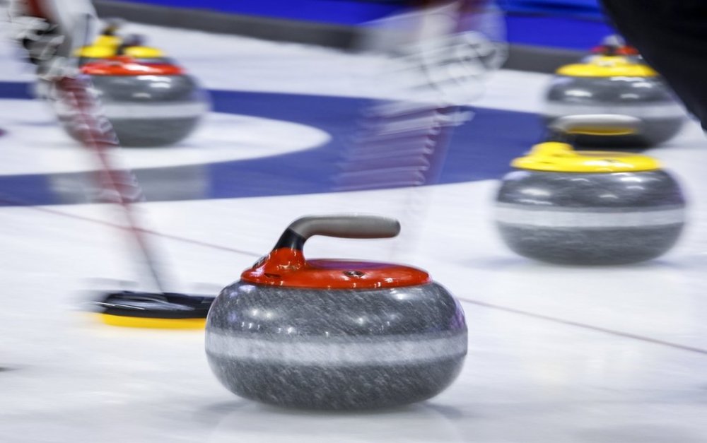 Players sweep a rock at the Tim Hortons Brier in Lethbridge, Alta. on March 6, 2022. Of the 98 schools in the Canadian Collegiate Athletic Association, there are just 14 men's curling teams and a dozen women's teams this season. THE CANADIAN PRESS/Jeff McIntosh