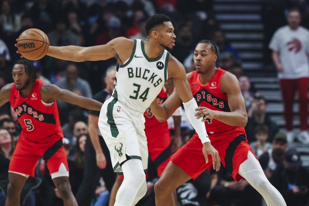 Milwaukee Bucks' Giannis Antetokounmpo (34) looks for options with pressure from Toronto Raptors' Scottie Barnes (4) during first half NBA basketball action in Toronto on Friday, October 24, 2025. THE CANADIAN PRESS/Nick Iwanyshyn