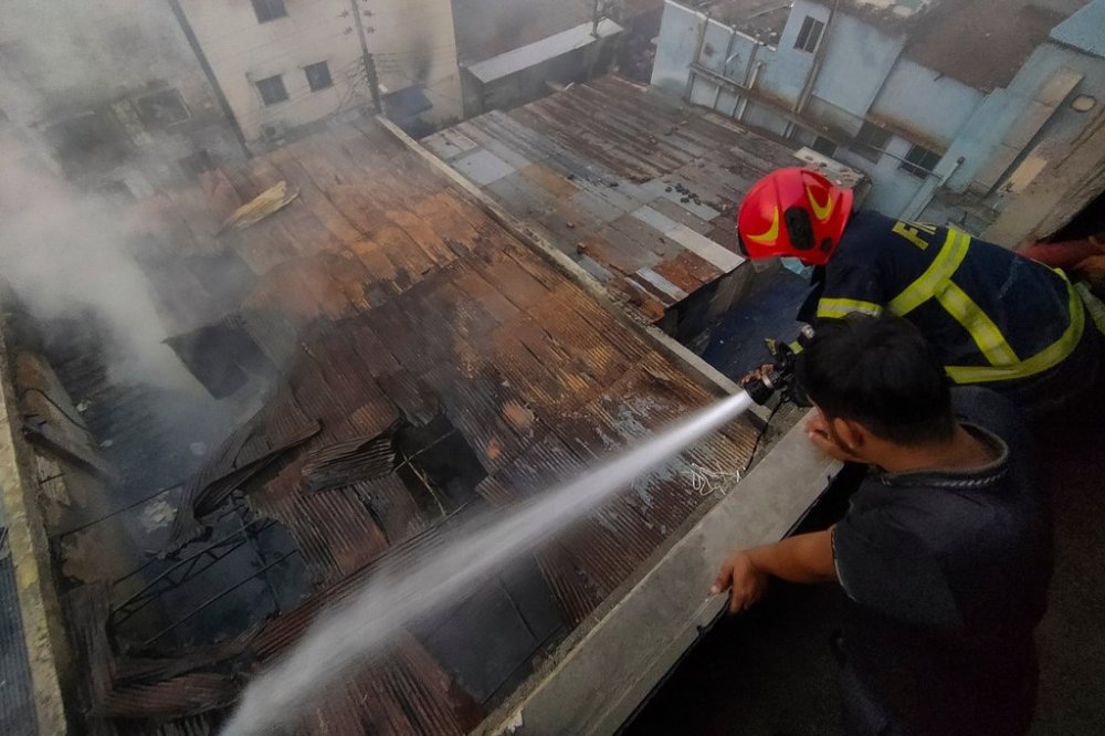 A firefighter sprays water to douse the flames after a fire broke out at a chemical warehouse and garment factory in Mirpur, Dhaka, Bangladesh, Tuesday, Oct. 14, 2025. (AP Photo/Mahmud Hossain Opu)