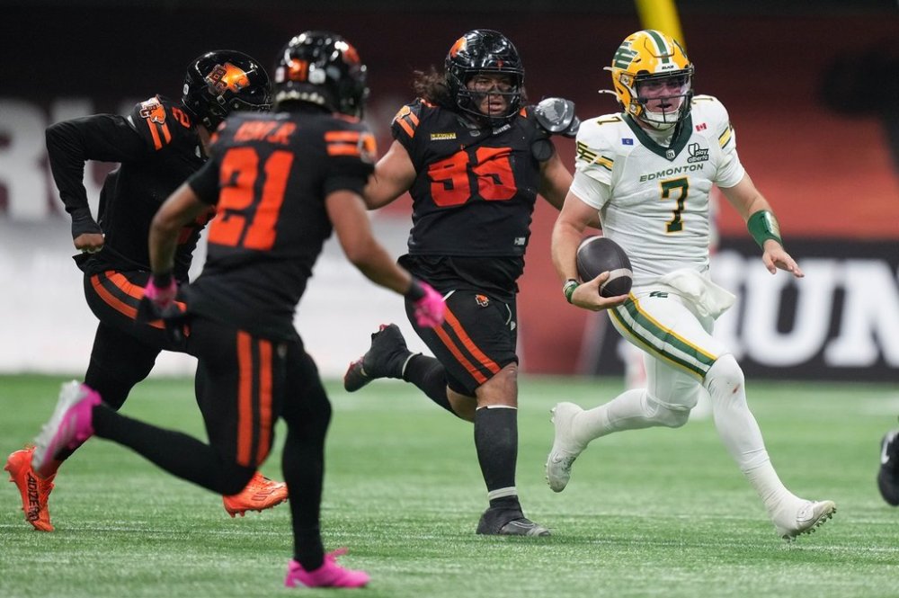 Edmonton Elks quarterback Cody Fajardo (7) runs with the ball as he's pursued by B.C. Lions' Jonah Tavai (99) and Josh Woods (2) during the first half of a CFL football game, in Vancouver, on Friday, October 17, 2025. THE CANADIAN PRESS/Darryl Dyck