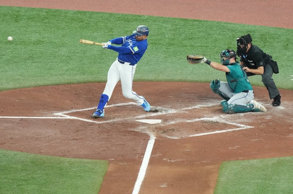 Toronto Blue Jays right fielder Anthony Santander (25) hits a single ruled as a double on the play in front of Seattle Mariners catcher Cal Raleigh (29) during second inning American League Championship Series baseball action in Toronto on Sunday, Oct. 12, 2025. THE CANADIAN PRESS/Nathan Denette