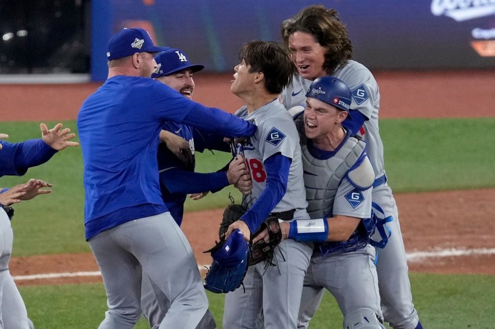 Teammates surround Los Angeles Dodgers' pitcher Yoshinobu Yamamoto, center, as they celebrate their win in Game 7 of baseball's World Series against the Toronto Blue Jays, Sunday, Nov. 2, 2025, in Toronto. (AP Photo/Ashley Landis)