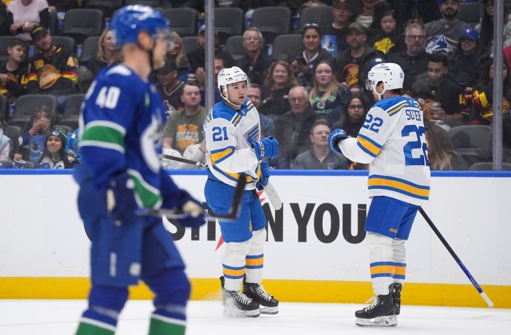 St. Louis Blues' Jimmy Snuggerud (21) and Pius Suter (22) celebrate Snuggerud's goal as Vancouver Canucks' Elias Pettersson skates past during the first period of an NHL hockey game in Vancouver, on Monday, Oct. 13, 2025. THE CANADIAN PRESS/Darryl Dyck