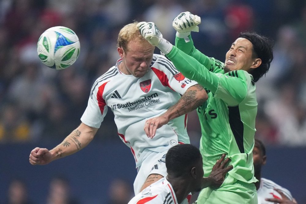 Vancouver Whitecaps' goalkeeper Yohei Takaoka, right, punches the ball away from FC Dallas' Samuel Sarver during the first half of an MLS soccer match, in Vancouver, on Saturday, Oct. 18, 2025. THE CANADIAN PRESS/Darryl Dyck