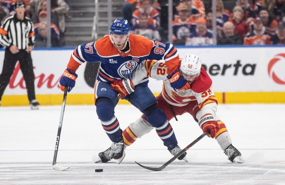 Calgary Flames' MacKenzie Weegar (52) and Edmonton Oilers' Connor McDavid (97) battle for the puck during overtime NHL action, in Edmonton on Wednesday, Oct. 8, 2025. THE CANADIAN PRESS/Jason Franson