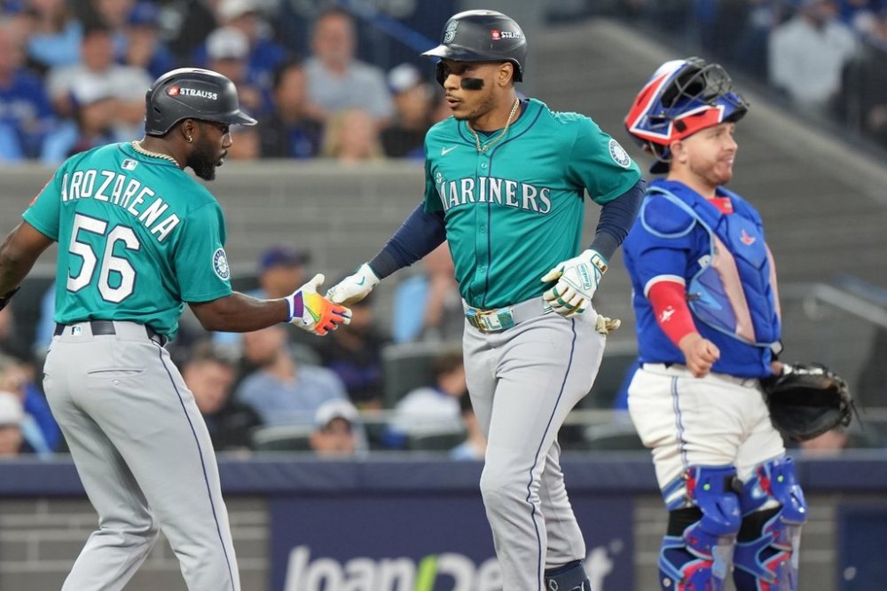 Seattle Mariners second baseman Jorge Polanco celebrates his three-run homer with teammate Randy Arozarena (56) as Toronto Blue Jays catcher Alejandro Kirk (30) looks on during fifth inning American League Championship Series baseball action in Toronto on Monday, Oct. 13, 2025. THE CANADIAN PRESS/Frank Gunn