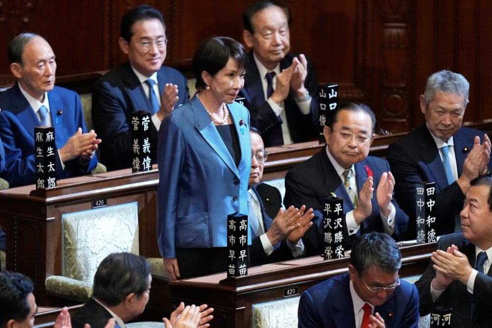 Lawmakers applaud as Sanae Takaichi, standing, was elected as Japan's new prime minister during the extraordinary session of the lower house, in Tokyo, Japan, Tuesday, Oct. 21, 2025.(AP Photo/Eugene Hoshiko)