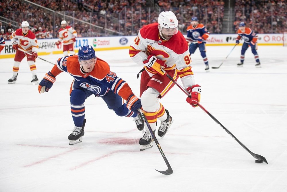 Calgary Flames' Nazem Kadri (91) and Edmonton Oilers' Ty Emberson (49) battle for the puck during third period NHL action, in Edmonton on Wednesday, October 8, 2025. THE CANADIAN PRESS/Jason Franson