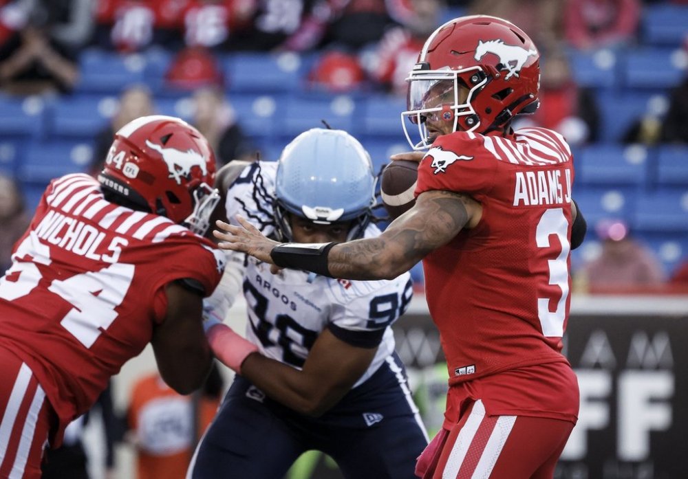 Toronto Argonauts' Da'Marcus Johnson, centre, closes in on Calgary Stampeders quarterback Vernon Adams Jr. during first half CFL football action in Calgary, Saturday, Oct. 18, 2025. THE CANADIAN PRESS/Jeff McIntosh