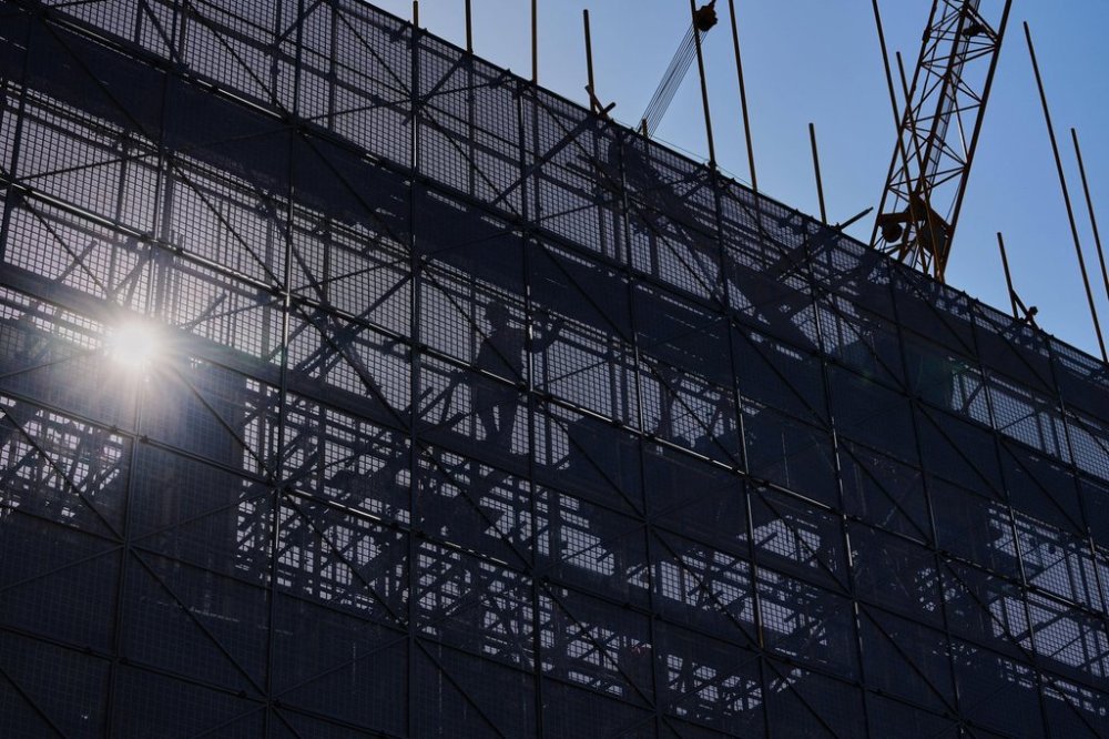 A worker installs scaffolding at a building under construction at the capital popular shopping district, in Beijing, Tuesday, Oct. 21, 2025. (AP Photo/Andy Wong)