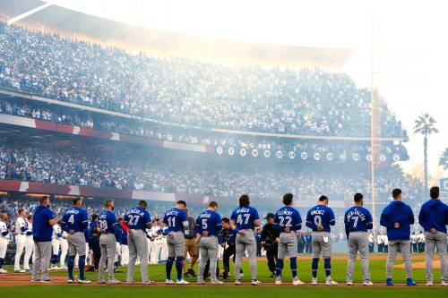 The Toronto Blue Jays and Los Angeles Dodgers listen to the singing of the national anthems ahead of the first inning in Game 3 of the World Series playoff in Los Angeles on Oct. 27. (Frank Gunn/The Canadian Press files)