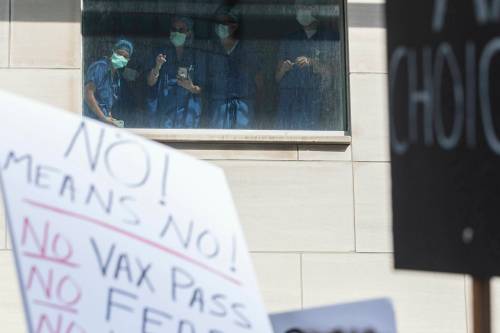 Health-care workers watch from a window as demonstrators gather outside Toronto General Hospital in September 2021 to protest against COVID-19 vaccines, COVID-19 vaccine passports and COVID-19 related restrictions. (The Canadian Press files)