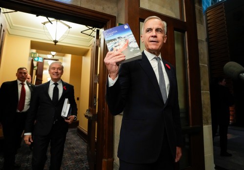Prime Minister Mark Carney holds up a copy of the budget as he and Minister of Finance and National Revenue Francois-Philippe Champagne make their way to the House of Commons for the tabling of the federal budget on Parliament Hill in Ottawa on Nov. 4. (The Canadian Press files)