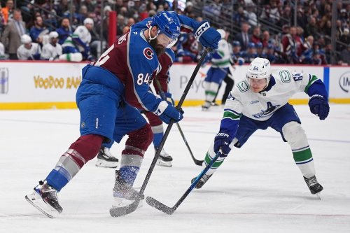 Colorado Avalanche defenseman Brent Burns, left, clears the puck as Vancouver Canucks center David Kampf defends in the second period of an NHL hockey game, Tuesday, Dec. 2, 2025, in Denver. (AP Photo/David Zalubowski)