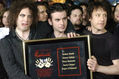 FILE - Robert Smith, left, Simon Gallup, center, and Perry Bamonte of British rock group The Cure hold a plaque after being inducted into Hollywood's Rockwalk in Los Angeles, Friday, April 30, 2004. (AP Photo/Chris Pizzello, File)